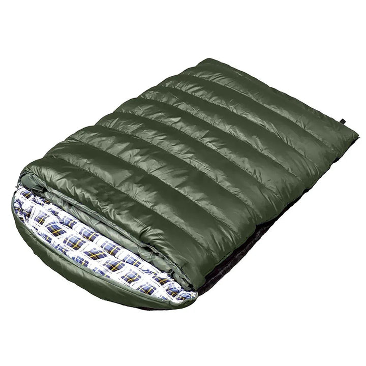 Two adults resting comfortably inside a large double sleeping bag outdoors at night.