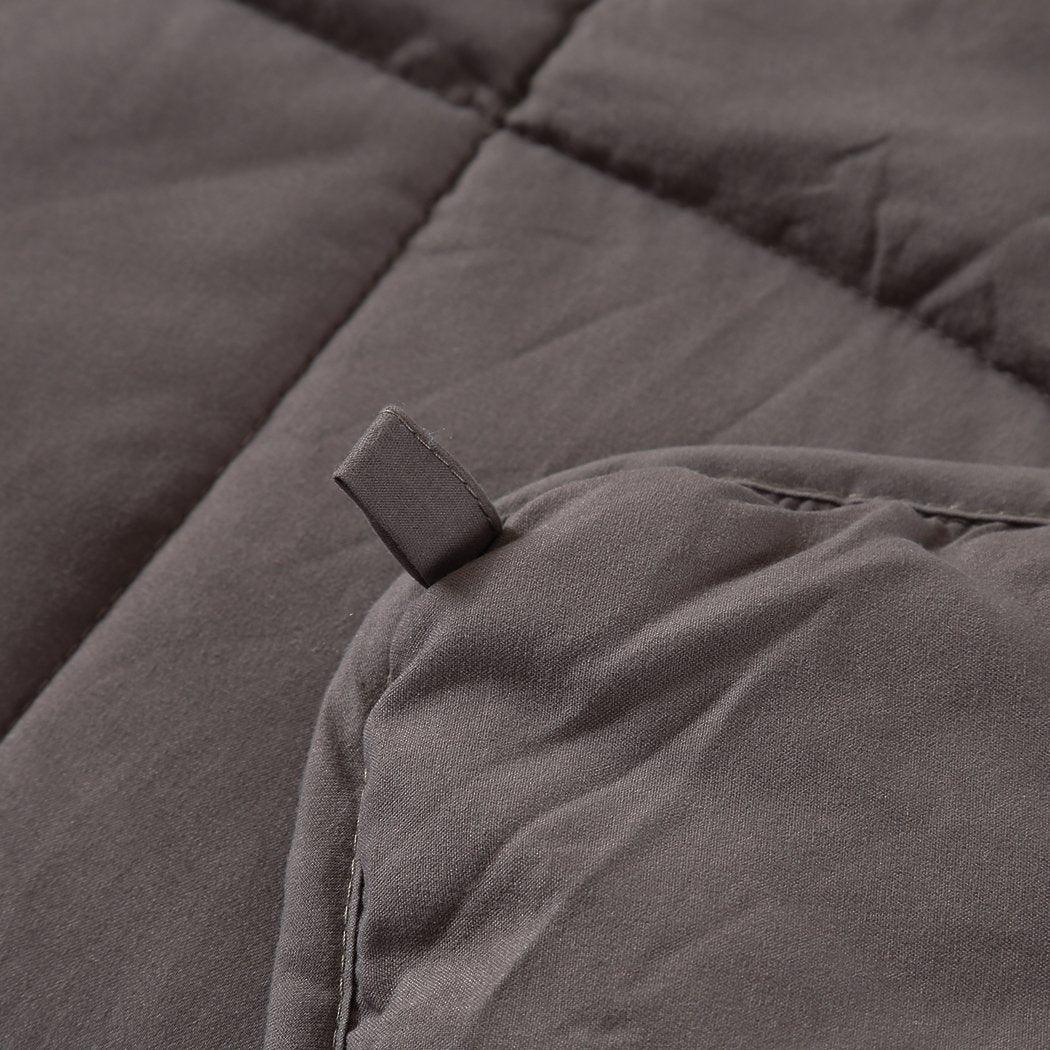 Person comfortably wrapped in grey weighted blanket, demonstrating its relaxing use.