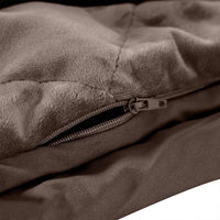 Soft mink colored weighted blanket draped over chair in minimalist styled bedroom corner.