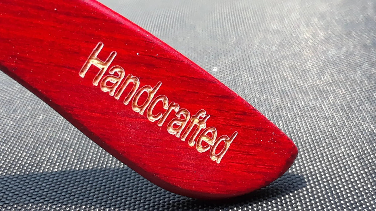 Red bamboo tortoise framed sunglasses presented on flat surface with soft lighting.
