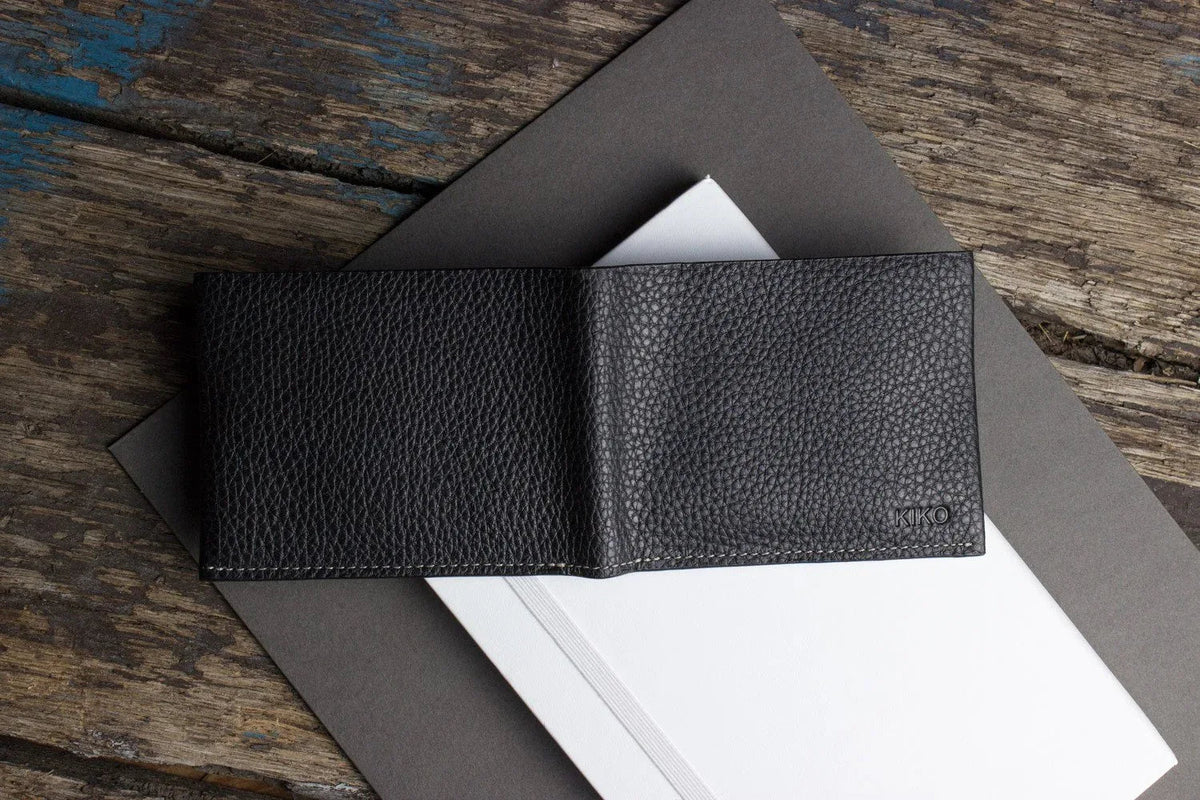 Hand holding open black leather wallet revealing card slots and compartments.