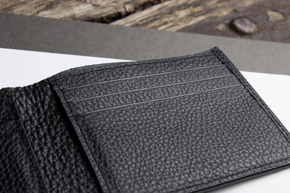 Black wallet interior with multiple compartments and self-lined bill section.