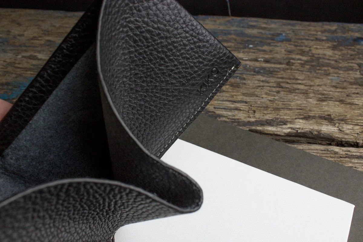Close-up of black leather wallet corner highlighting detailed stitching.