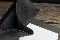 Close-up of black leather wallet corner highlighting detailed stitching.