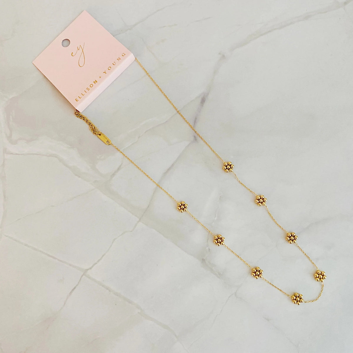 Golden bead flower necklace displayed on a flat surface, showing detailed flower beads.
