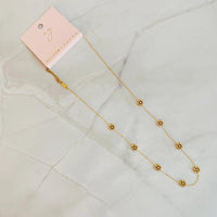 Golden bead flower necklace displayed on a flat surface, showing detailed flower beads.