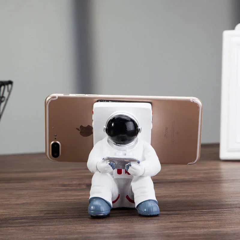 Close-up of the astronaut stand holding a smartphone on a wooden desk.