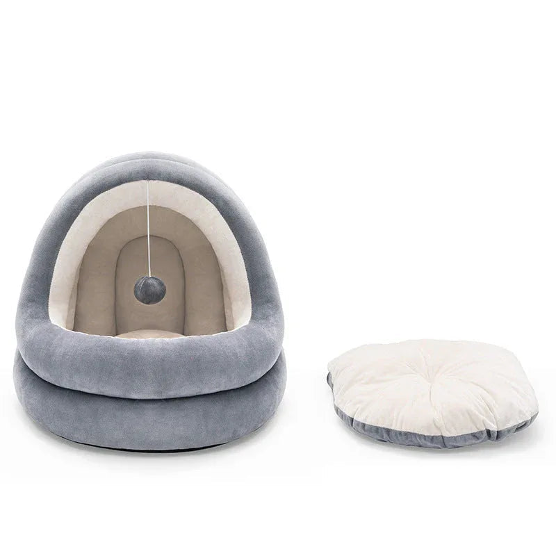 Small cat bed in neutral tones placed near household plants, showcasing removable mattress.