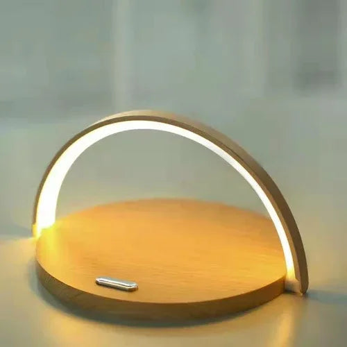 Sleek black wireless charger block holds a smartphone upright while charging on a white tabletop.