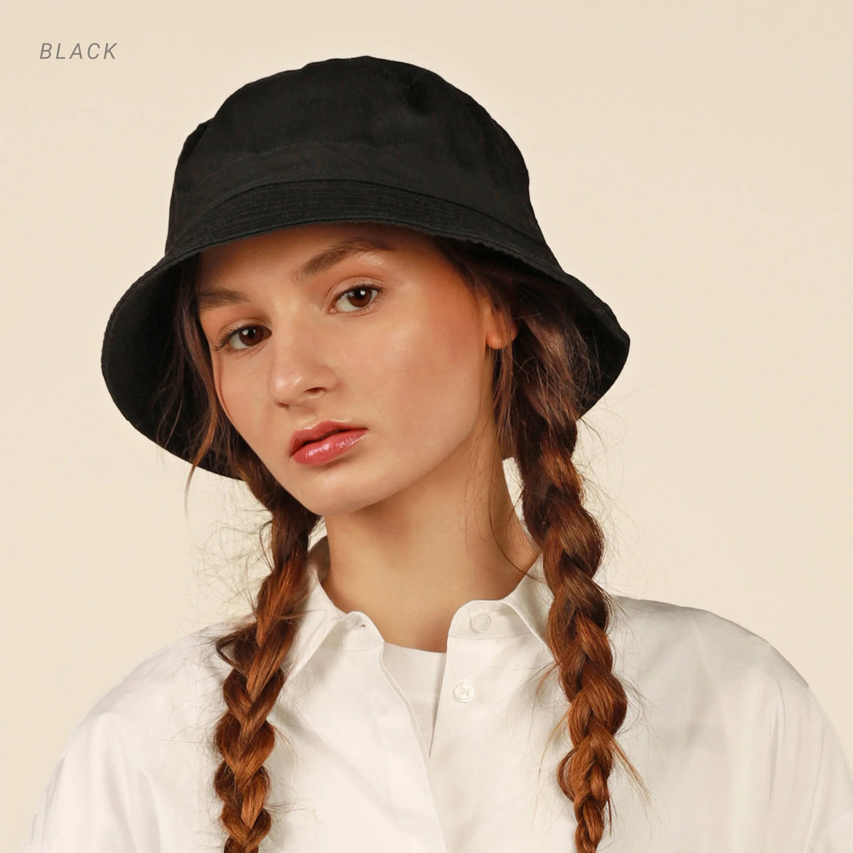 Black and white photo of model wearing black cotton bucket hat, side profile.