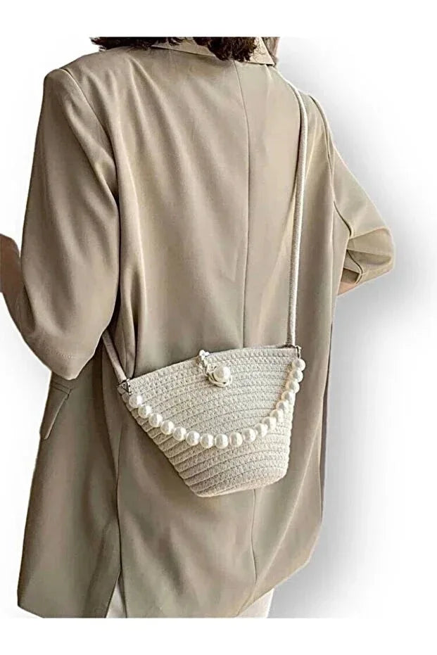 Off white women's shoulder bag featuring elegant pearl detailing on a textured fabric background.