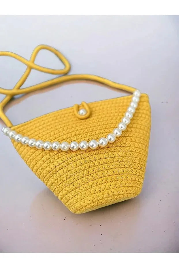 Close-up of yellow knitted fabric and pearl accents on an elegant women's shoulder bag