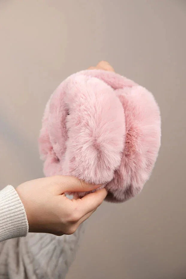 Folded soft pink plush earmuffs compactly arranged to illustrate portability and lightweight style.