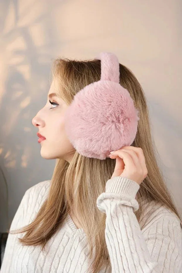 Soft pink plush earmuffs worn on a head form, demonstrating full ear coverage and cold weather protection.
