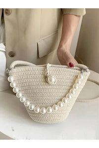 Top view of the bag emphasizing its simple clasp and pearl embellishments on the strap.