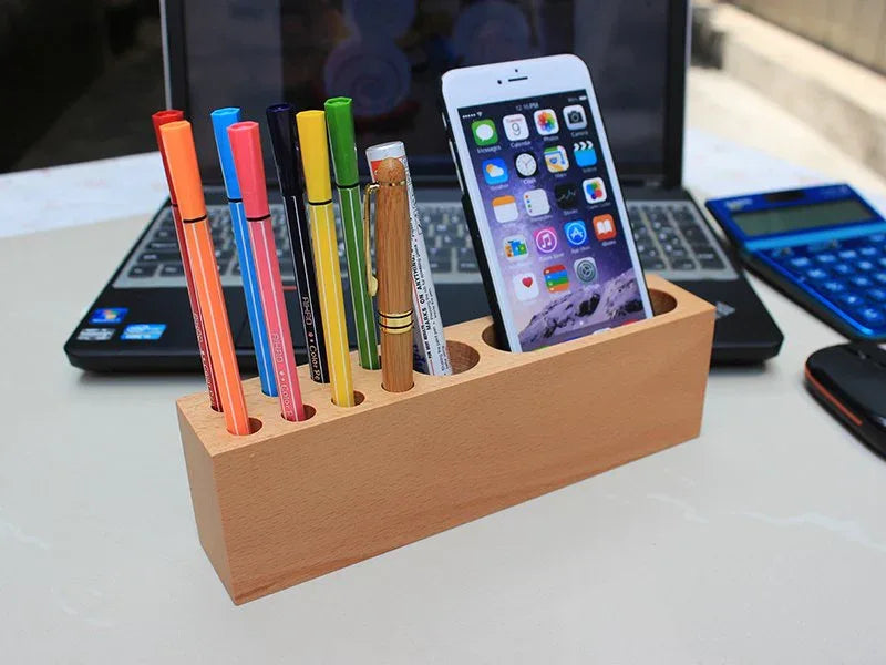 Close-up of wooden phone holder and pen container showing smooth beech wood texture and smartphone slot.