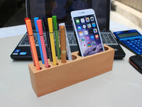 Close-up of wooden phone holder and pen container showing smooth beech wood texture and smartphone slot.