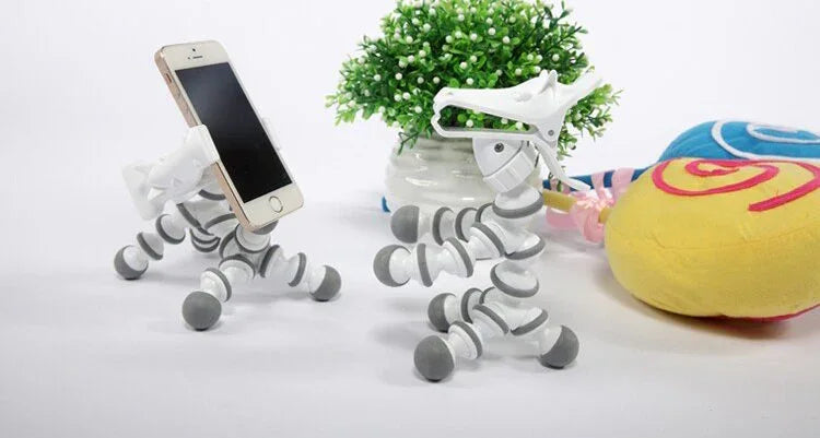 Various flexible animal phone stands in different colors displayed on a white surface.