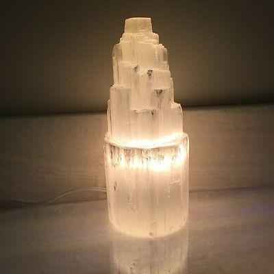 Close-up of selenite skyscraper lamp with light shining through translucent crystal