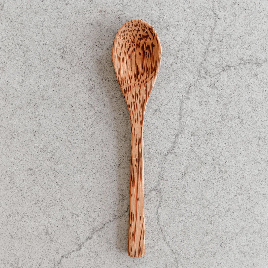 Wooden spoons displayed with a coconut bowl and ice cream, highlighting eco-friendly kitchenware.