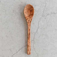 Wooden spoons displayed with a coconut bowl and ice cream, highlighting eco-friendly kitchenware.