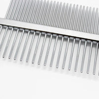 Close-up of red pet grooming comb showing dense and sparse stainless steel teeth and hollow handle design