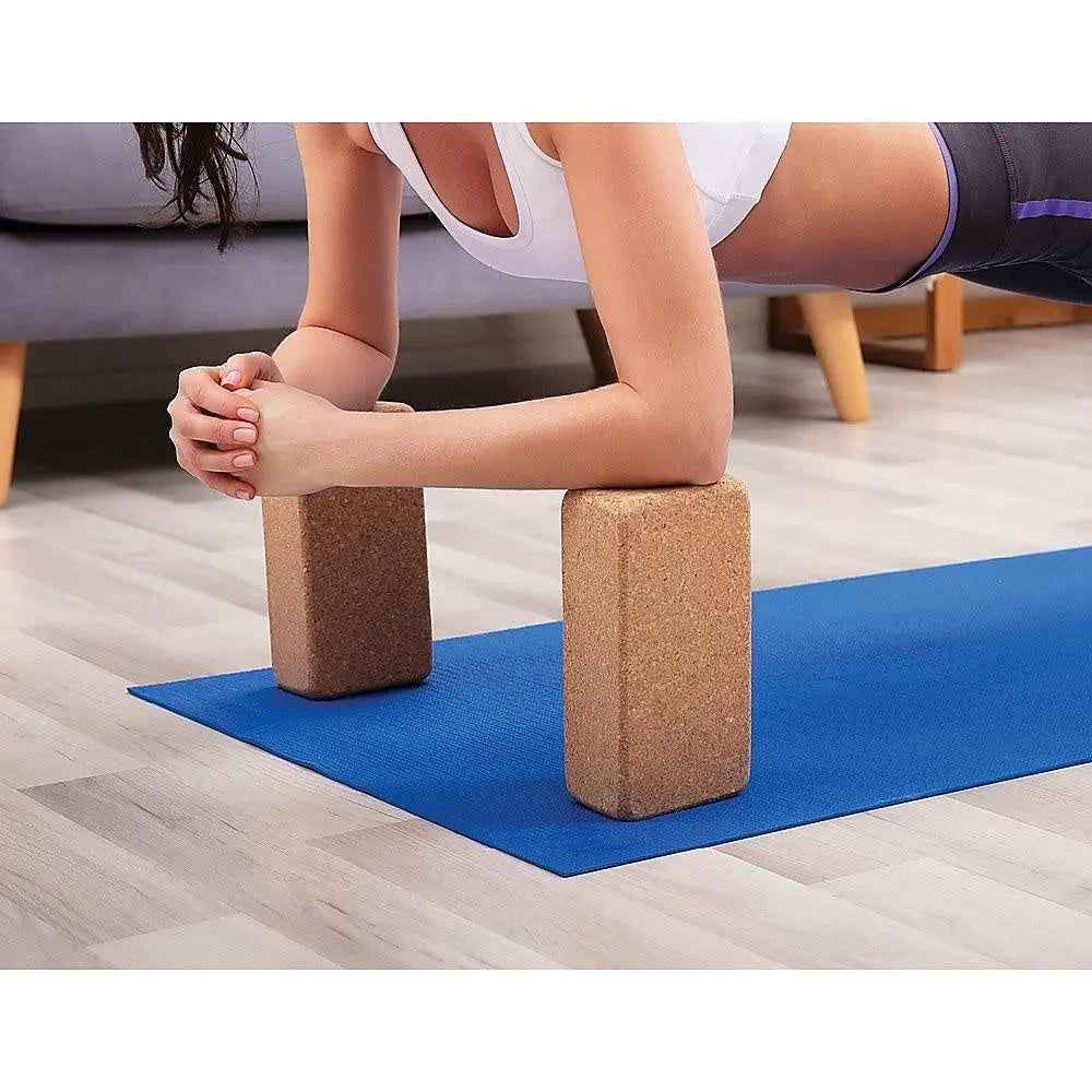 Two natural cork yoga blocks with rounded edges, placed side by side on a light background.