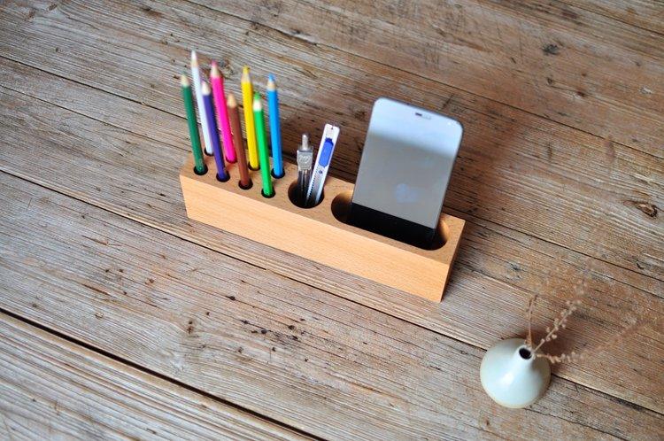 Side view of wood phone holder and pen container with a smartphone placed horizontally inside.