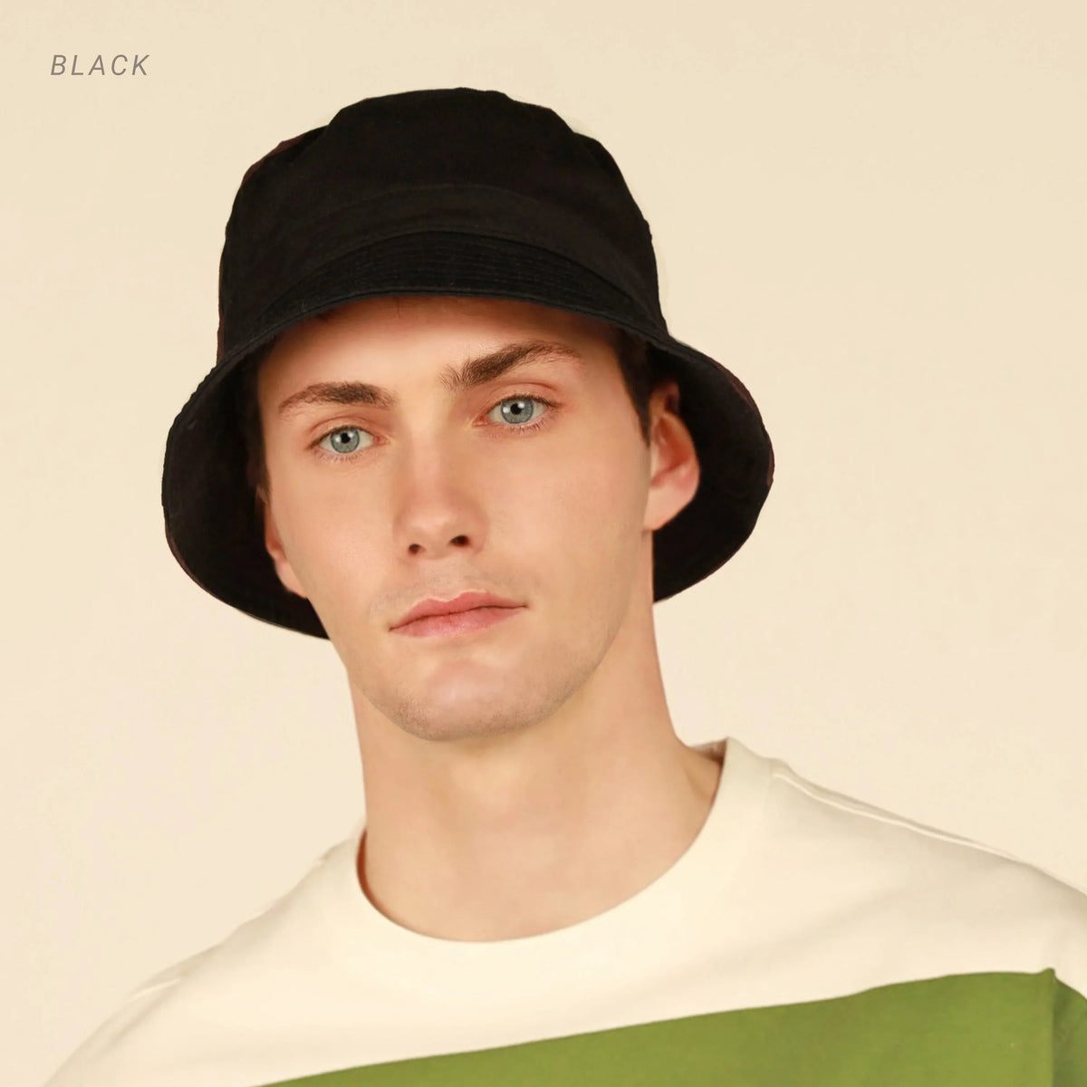 Model wearing black cotton bucket hat with flat brim against plain background.