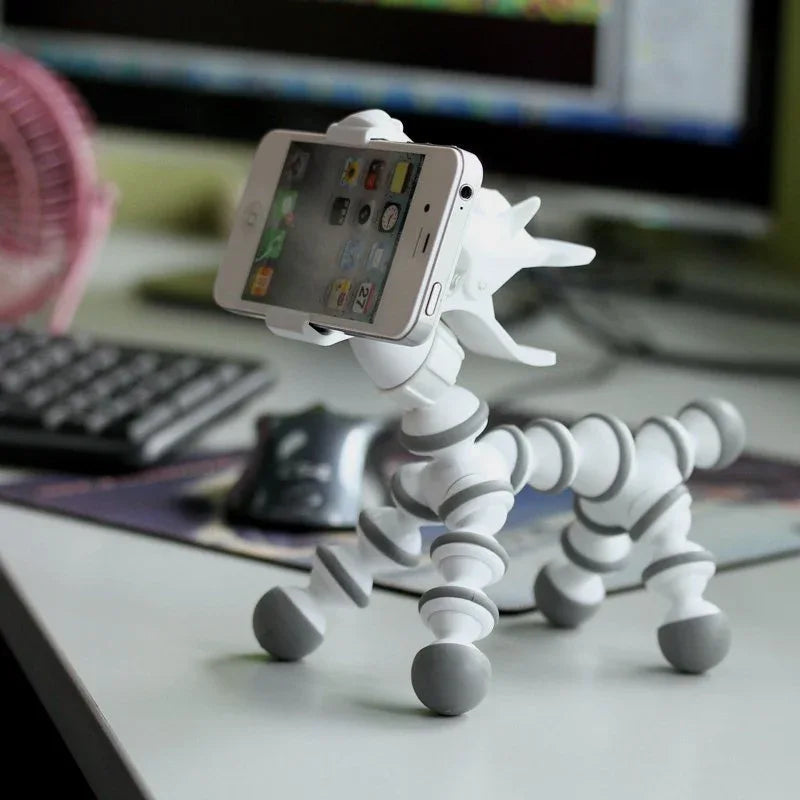 Flexible cute animal-shaped phone stand holding a smartphone upright, light background.