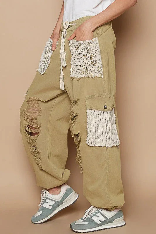 Front view of distressed washed jeans with crochet patches on a mannequin against a neutral background.