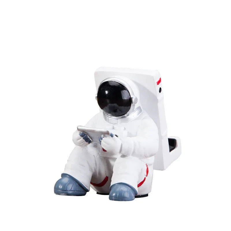White resin astronaut-shaped mobile phone stand viewed from the front on a white background.