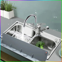 Washing vegetables in kitchen sink with silicone water baffle protecting surrounding counter.