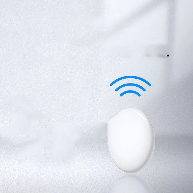 Bluetooth key finder connected to a key ring next to a smartphone on a wooden table.