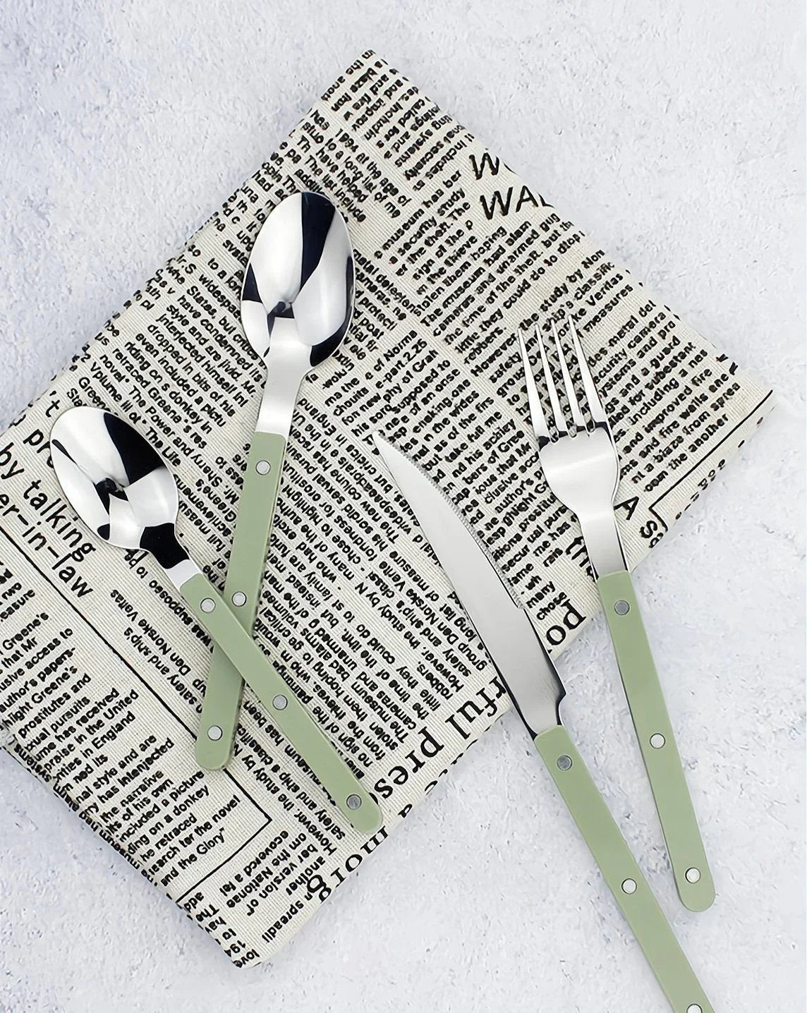 Top view of 8-piece modern flatware set featuring ivory handles arranged symmetrically on a wooden board.