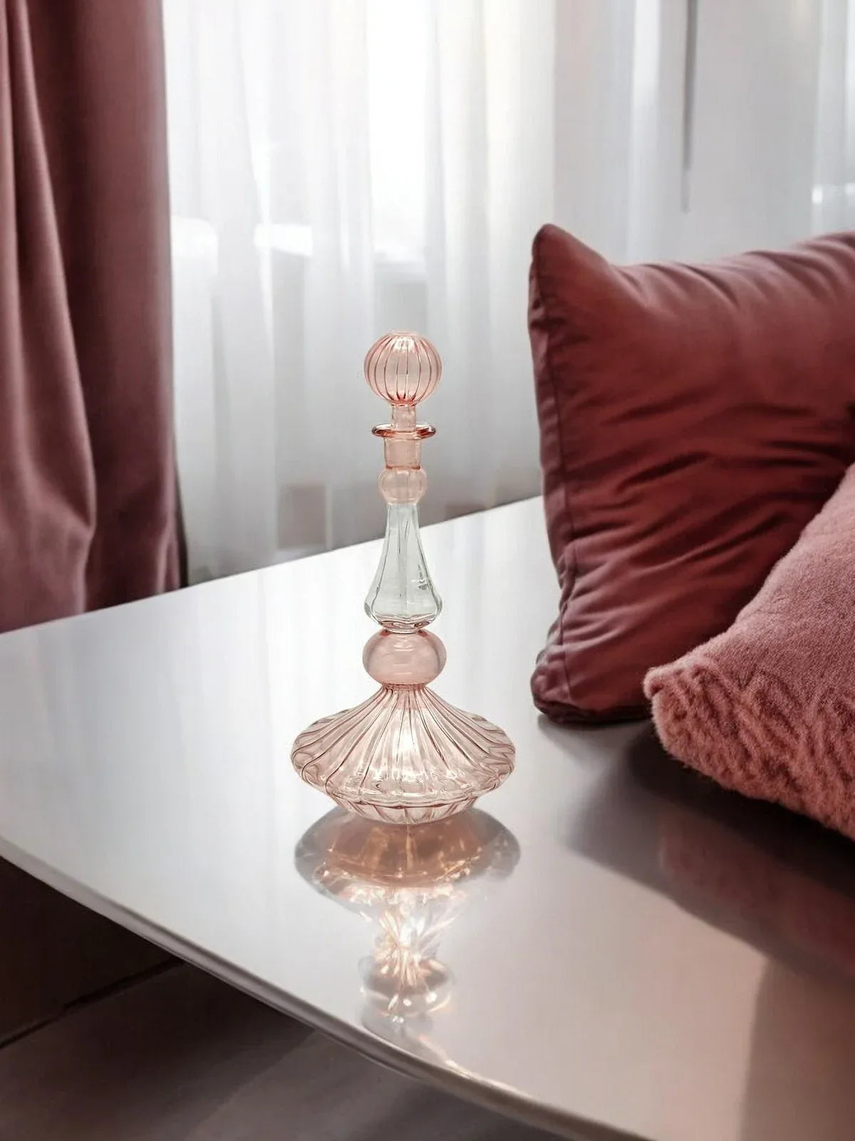 Hand painted blown glass bottle with ornate floral design displayed on a wooden surface.