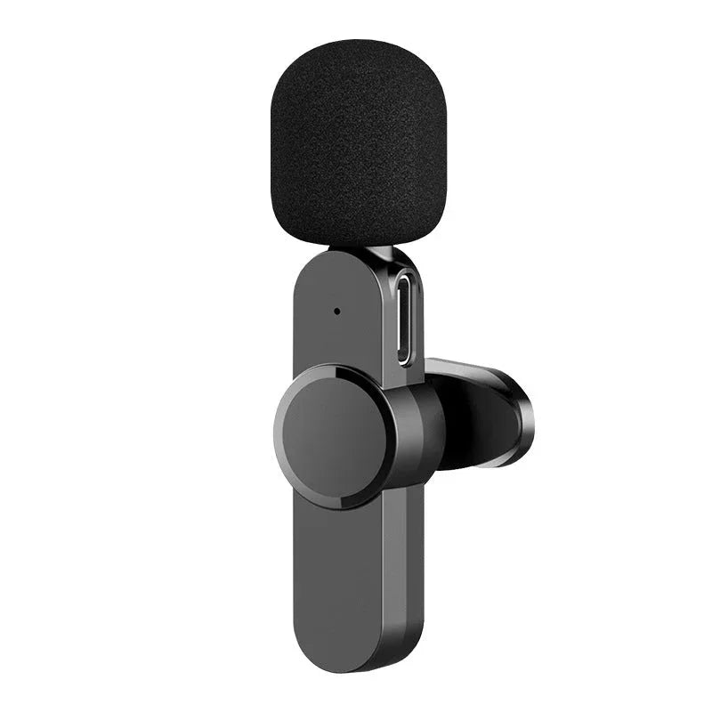 Wireless lavalier microphone with lapel clip displayed beside a smartphone.