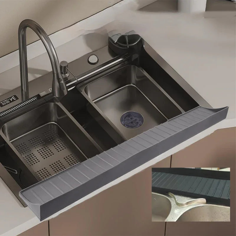 Gray silicone sink protective pad placed inside a kitchen sink with water droplets on surface.
