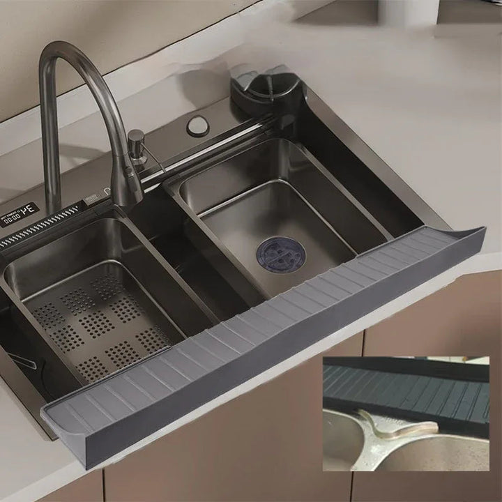 Gray silicone sink protective pad placed inside a kitchen sink with water droplets on surface.