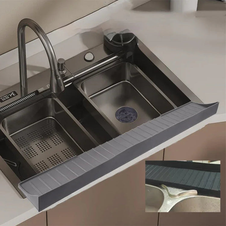 Gray silicone sink protective pad placed inside a kitchen sink with water droplets on surface.