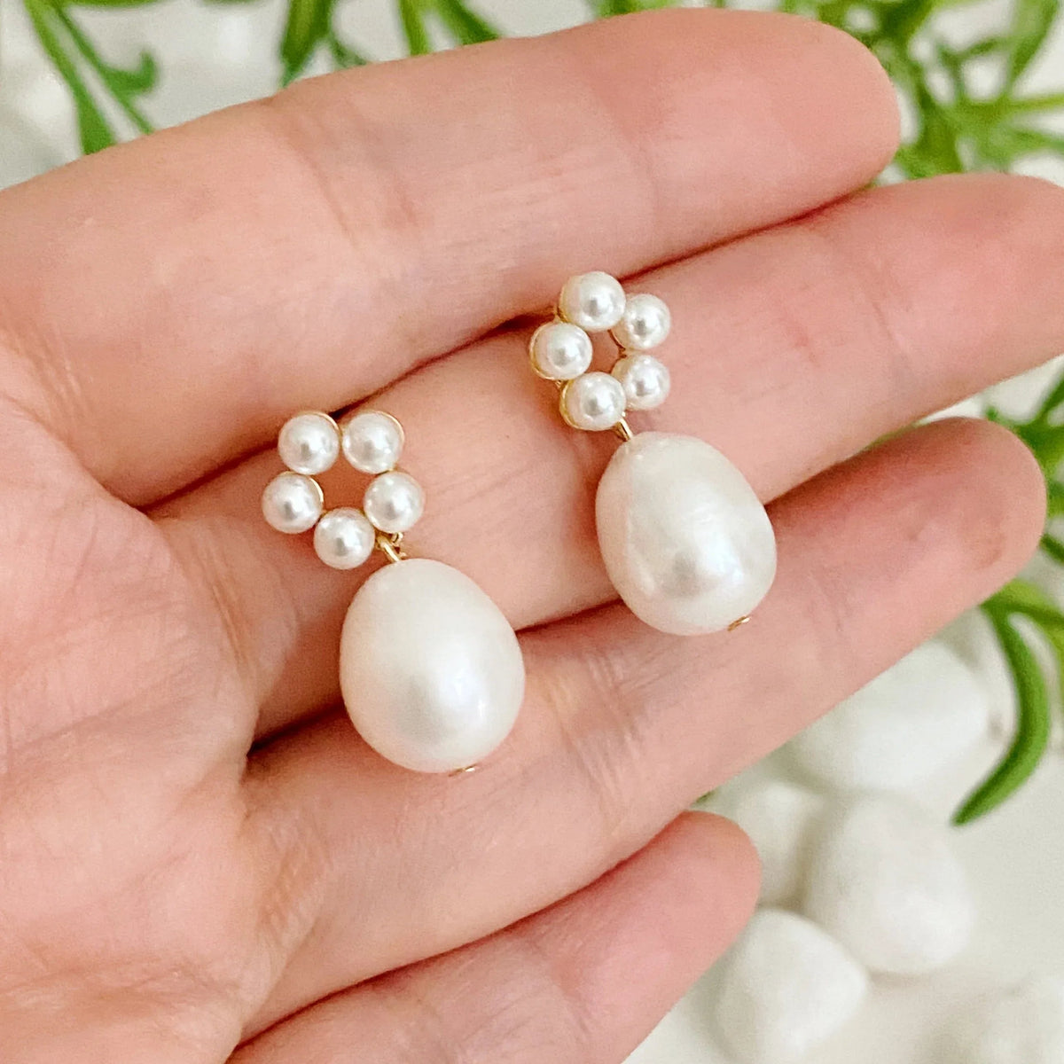 Pair of Blooming Pearl Drop Earrings placed on light beige surface showing shine and texture.