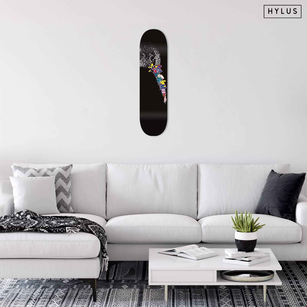 Living room with graffiti hummingbird skateboard displayed on white wall above sofa