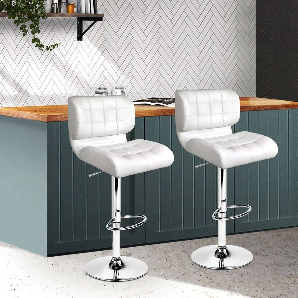 Bar stools with adjustable chrome bases, showing footrests and plush white seats.