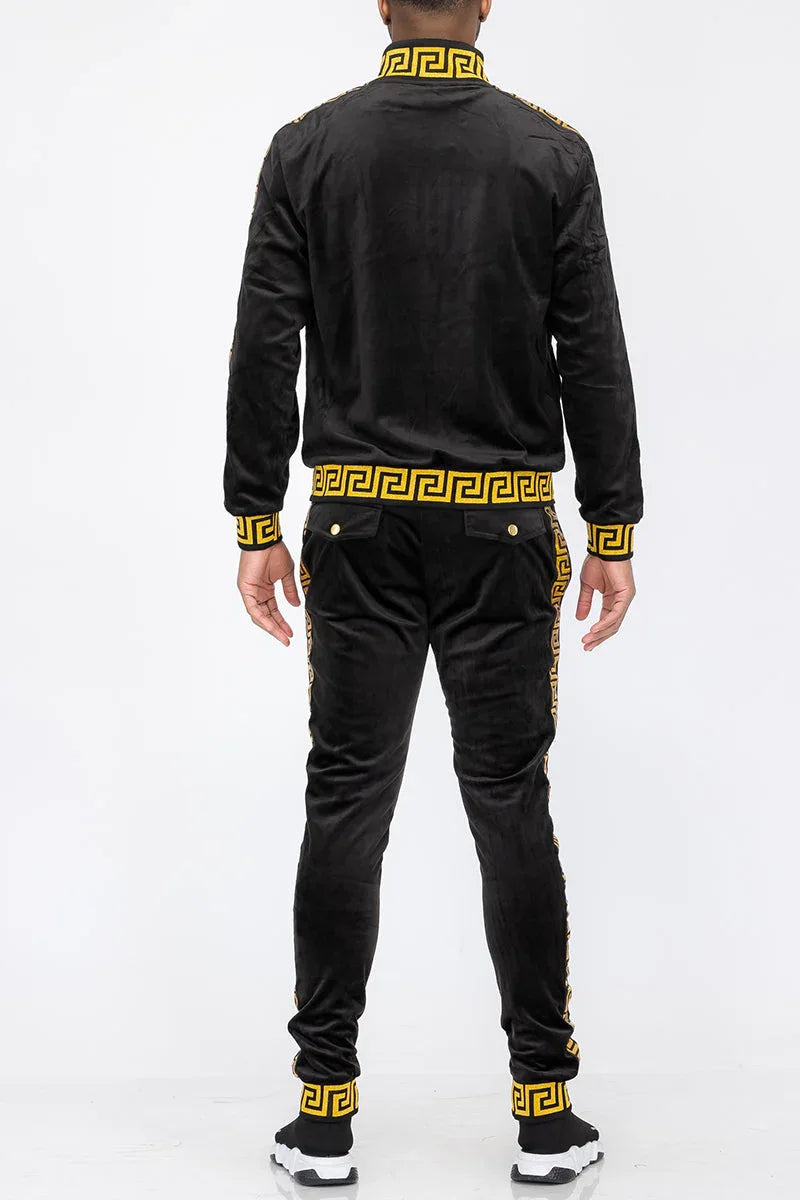 Black velour track pants with gold stripes hanging, showing elastic waistband and cuffs.