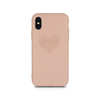 Close-up of compostable pastel pink phone case featuring a small engraved heart design.