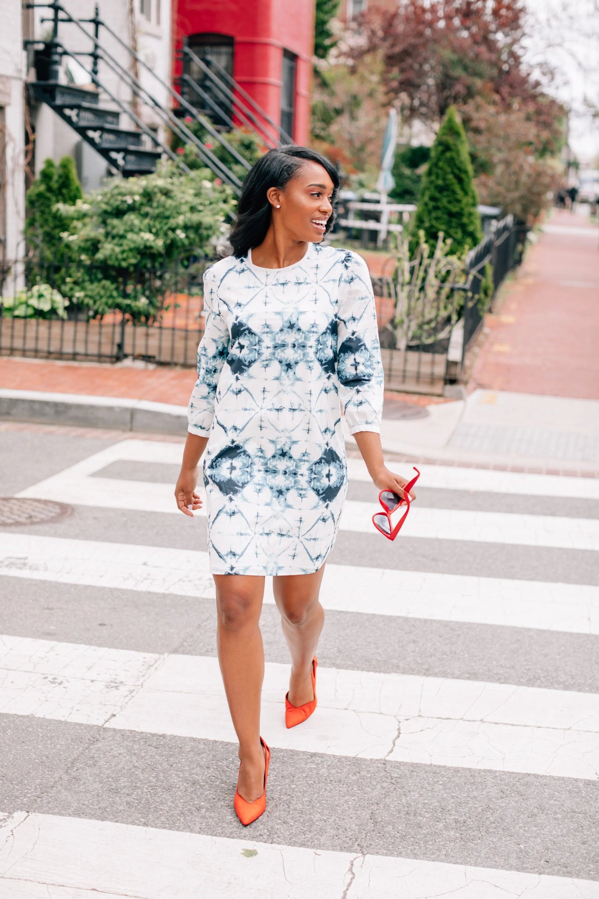Model wearing Inkwell Dress with 3/4 sleeves and tie dye print with polka dots, standing near window.