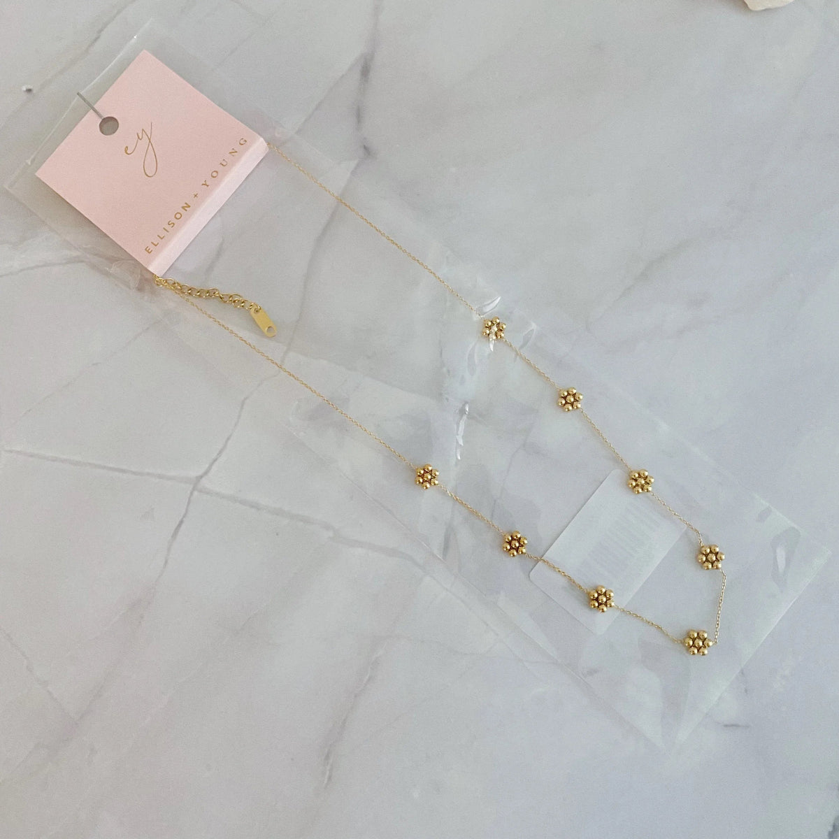 Close-up of necklace clasp and extender chain in gold finish on white background.