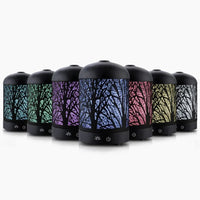 Black Devanti aroma diffuser with enchanted forest pattern on top, placed on wooden surface.