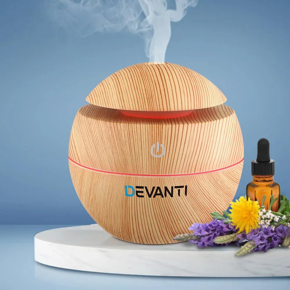 Wood grain aromatherapy diffuser with multi-color LED lights on a wooden surface.