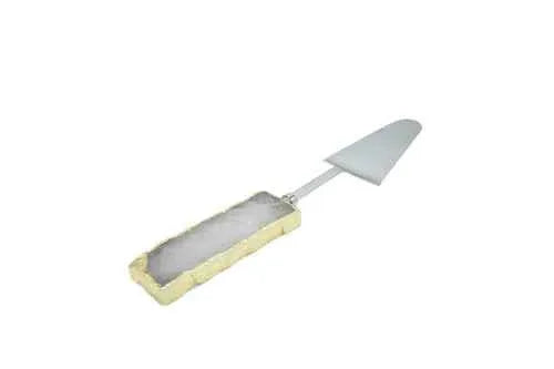 Gemstone cake server with gold trim resting on a white cloth